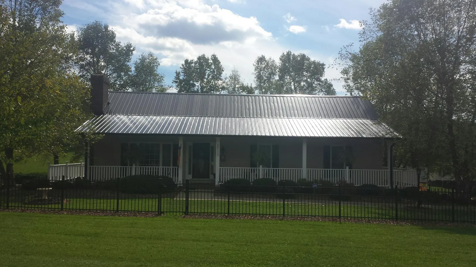 Gray metal roof on a brick ranch with a full width front porch — Gutter Guard Installation work by our crew in Russellville